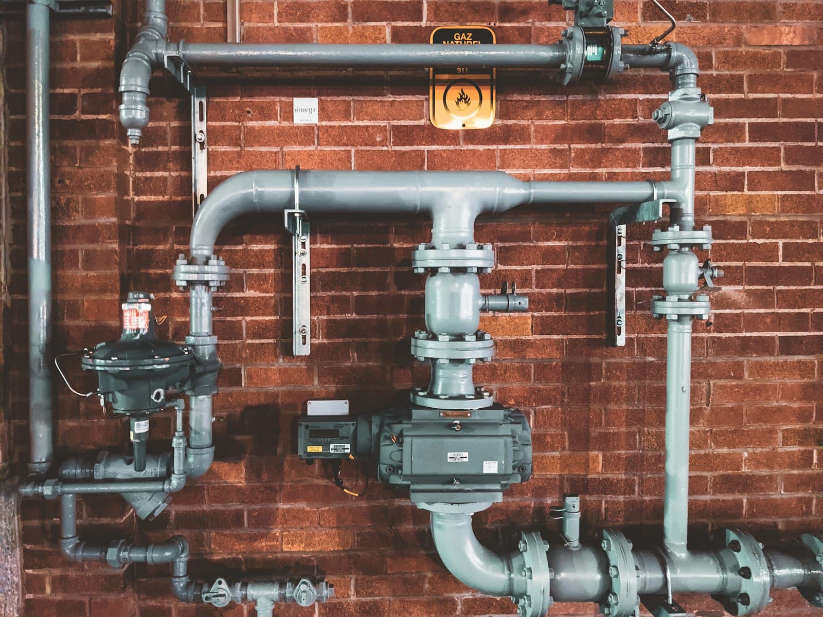 Commercial gas piping and regulators mounted on a brick mechanical wall