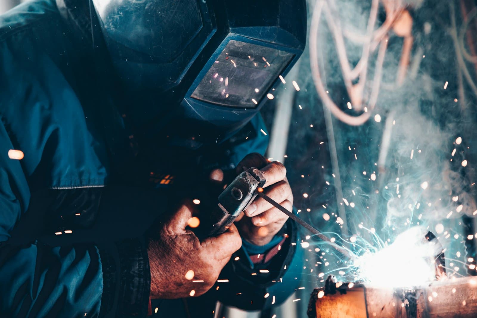 Tradesman welding pipe with sparks in a workshop